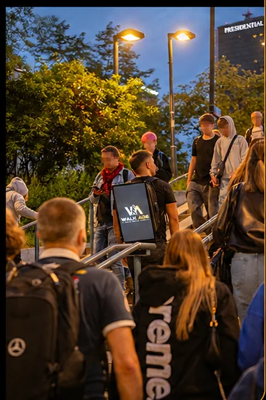Nośnik WALK ADS wśród przechodniów wychodzących ze stacji wieczorem